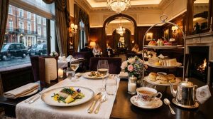 Elegant fine dining restaurant in a luxury Mayfair London hotel, beautifully plated gourmet dishes, afternoon tea setup with pastries and teacups
